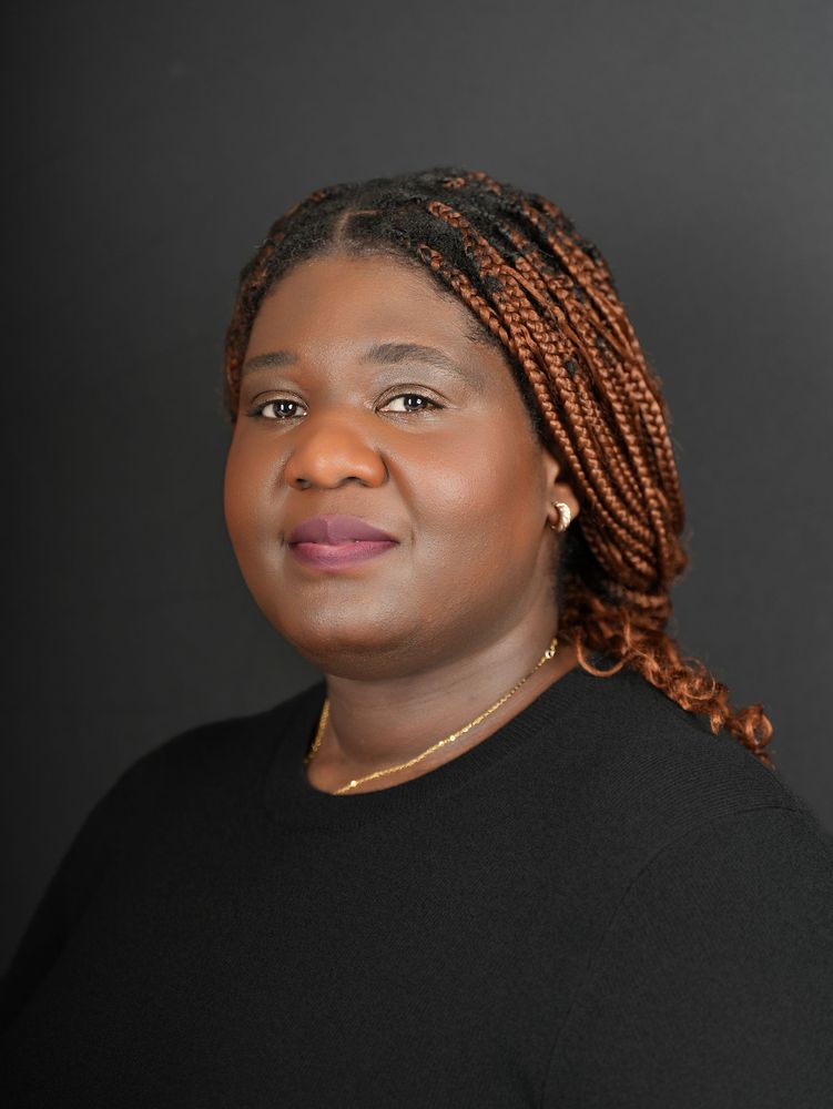 Headshot of a woman with braids on a dark backdrop