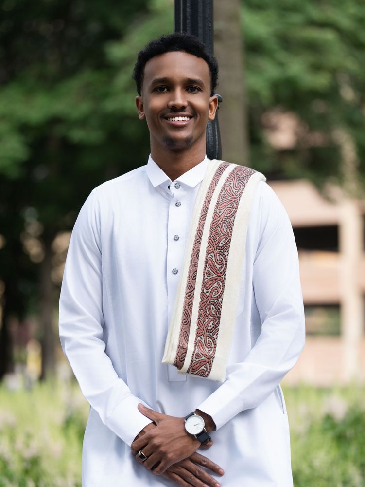 Smiling young man in a white robe with a patterned scarf